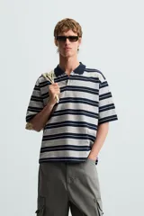 Polo de hombre corte holgado con cuello solapa y cierre de botones. Diseño a rayas horizontales grises y azul marino.