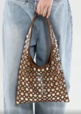 Bolso tipo tote de cuero sintético color borgoña, con apliques metálicos plateados y asa corta.