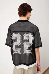 Remera negra de malla con cuello redondo ribeteado y estampado del número 22 en plateado. Corte oversized con hombros caídos y bajo recto.