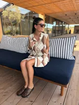 Vestido camisero corto con estampado de rombos en tonos beige, marrón y blanco. Tiene cuello camisero, cierre frontal con botones y corte holgado.