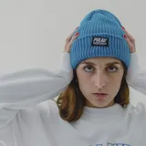 Gorro de lana blanco con etiqueta negra con el logo de la marca Pulau.