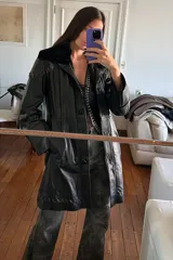 Tapado largo de cuero negro con cuello de piel sintética desmontable y detalles de pasamanería marrón vintage en hombros y espalda. Se convierte en abrigo corto mediante un cierre.