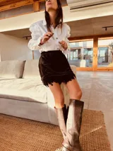 Minifalda negra de terciopelo con cintura elástica y ruedo con plumas.
