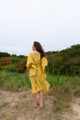 Vestido túnica amarillo con rayas verticales blancas, corte amplio, mangas cortas y lazo para ajustar en la cintura.