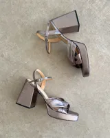 Sandalia de cuero vacuno color dorado, con plataforma y taco cuadrado. Presenta una tira delgada en el tobillo y detalle de nudo en la capellada.