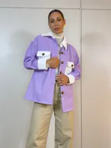 Sobre camisa lila con detalles en blanco, de corte holgado y mangas largas.