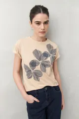 Remera blanca de manga corta con estampado floral en tonos dorados en el frente.