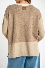 Sweater de punto color beige con mangas largas combinadas en tonos de marrón.
