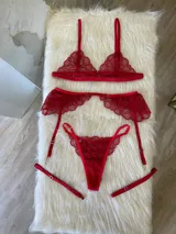 Conjunto de lencería rojo de encaje, compuesto por un bralette con breteles regulables, una tanga regulable con corte media less y un portaligas con volados.