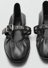 Zapato tipo bailarina color dorado, con punta redonda y tira sobre el empeine con hebilla metálica.