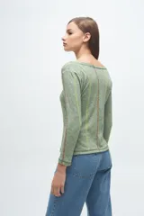 Remera gris de corte ajustado, con cuello redondo y mangas largas. Presenta líneas verticales bordadas en color verde claro y blanco.