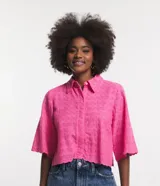 Camisa corta color rosa con textura de flores, escote camisero, manga corta, abotonado frontal y bajo con recorte ondulado.