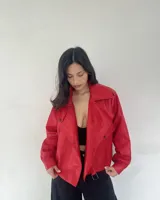 Campera roja de cuero sintético, con cuello solapa, cierre cruzado con botones a presión y cinturón con hebilla.