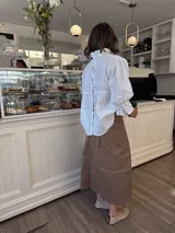 Blusa blanca de lino con cuello alto fruncido, mangas 3/4 con volados y detalle constructivo en el delantero con costuras a mano.