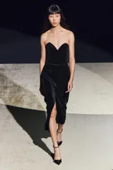Vestido midi negro de terciopelo, palabra de honor con escote corazón y hombros descubiertos. Tiene detalle de elástico tipo nido de abeja en la espalda y abertura en el bajo.