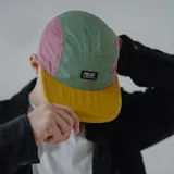 Gorra de cinco paneles con visera amarilla, frente verde y laterales rosados.