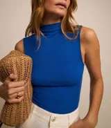 Blusa sin mangas color blanco, con cuello alto y textura acanalada.