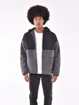 Campera con capucha, color gris oscuro, con paneles de tela tipo polar y tela lisa.