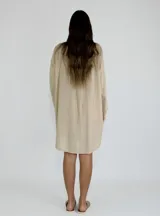 Vestido corto color beige con estampado de formas geométricas en relieve, escote en V y mangas largas.