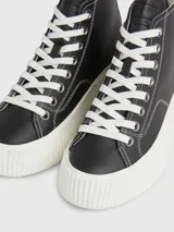 Zapatillas de caña alta Tommy Jeans, color negro, con cordones blancos y suela de plataforma blanca.