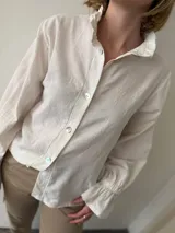 Camisa blanca de tusor de algodón con cuello mao, mangas largas abullonadas con lazo en los puños y botones de nácar. 