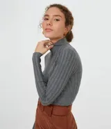 Polera de punto acanalado color salmón, con cuello alto y mangas largas.