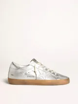 Zapatilla Golden Goose modelo Super-Star color plateado con estrella lateral y suela marrón.