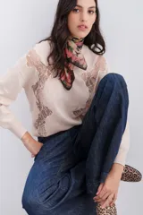 Sweater color beige con cuello redondo y mangas largas. Presenta paneles de encaje floral en la parte delantera y superior de la espalda.