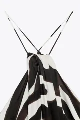 Vestido largo de viscosa con estampado animal en blanco y negro. Tiene cuello halter ajustable con lazos y bajo asimétrico.