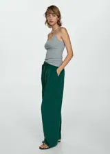 Pantalón verde esmeralda de corte ancho con pinzas, trabillas y cinturón decorativo con hebilla metálica.