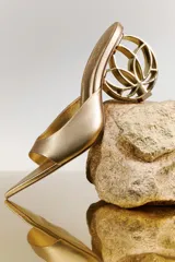 Sandalia mule dorada con punta fina y tacón medio/alto.