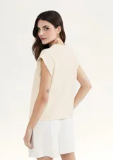 Blusa color crema de tejido acanalado, con cuello redondo y mangas cortas con hombreras.