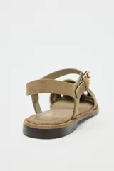Sandalias cangrejeras planas de serraje color beige, con puntera redondeada y cierre de hebilla lateral ajustable.