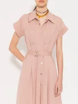 Vestido camisero midi color rosa, de corte recto, con cuello camisero, mangas cortas con puños, cinturón con hebilla forrada, cierre frontal con botones a tono y bolsillos plaqué en el pecho.