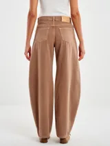 Pantalón de denim color marrón claro lavado, modelo relajado con cintura alta y pierna ancha tipo balloon que se afina ligeramente hacia el bajo.