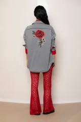 Camisa de jean celeste de corte oversize, con cuello clásico, cierre frontal con botones, bolsillo en el pecho y mangas largas con puños abotonados. Detalle de bordado en el puño.