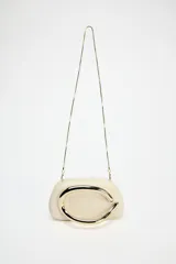 Bolso formato caja color crema con asa de cadena dorada para usar como bandolera. Cierre metálico dorado.
