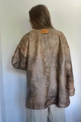 Campera de cuero color marrón con cuello redondo, cierre frontal con botones a presión, bolsillos laterales y corte holgado.