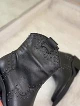 Botas cortas negras de cuero con punta fina, taco cuadrado y apliques de tachas plateadas.