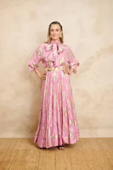 Vestido largo color rosa con estampado dorado, cuello con lazo y mangas largas.