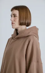 Buzo hoodie marrón de corte oversize, confeccionado en algodón rústico. Tiene capucha forrada, bolsillo tipo bomber con cierre en la manga y bolsillo canguro.