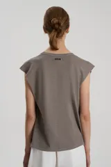 Musculosa color visón de jersey flamé de algodón, corte holgado, con escote redondo, detalle de tablas en hombros, sisas terminadas al corte, ruedo irregular con tajo lateral y bordado a tono en el frente.