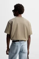 Camiseta color caqui de corte cuadrado, confeccionada en tejido de algodón pesado. Tiene cuello redondo y mangas cortas.
