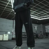 Pantalón de jogging negro, corte oversize, con la palabra "GAINS." estampada en blanco en el muslo izquierdo.