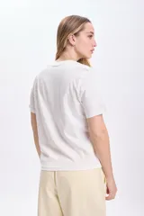 Remera blanca de algodón con cuello redondo y mangas cortas. Estampa de flores y texto en color negro.