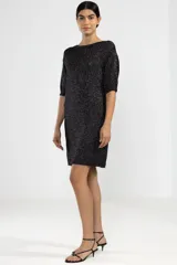 Vestido corto negro con brillos plateados, de tejido de punto con mangas 3/4 y corte recto.