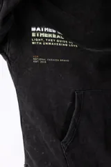 Buzo canguro negro con capucha, de corte oversize y estética lavada. Presenta un bolsillo tipo canguro y puños con orificio para el pulgar. Estampado con texto en el lateral izquierdo.