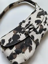 Cartera baguette con estampado de vaca en tonos blanco y marrón.