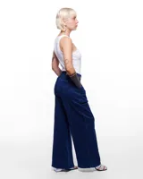 Pantalón de denim azul con corte sastrero de pierna ancha, tiro alto, cierre frontal invisible y pretina cruzada. Aplique de caballo/dragón en bronce hecho a mano y bordado negro del logo Temblad en la parte trasera.