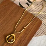 Set de tres collares dorados con dijes de piedra ojo de tigre con diferentes diseños: sol con strass, lágrima y abanico.